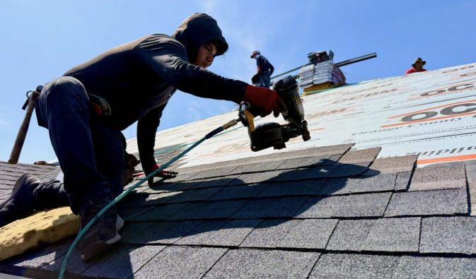 Roof Installation in Houston, Texas |  Southern Roofing Solutions Crew Roofing crew member using nail gun to install shingles on Houston, Texas home